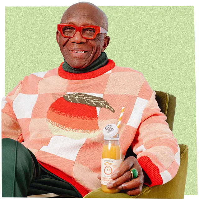 a man wearing big knitwear drinkng an innocent smoothie